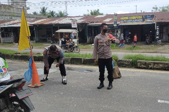 Petugas membantu masyarakat tambal lobang di jalan